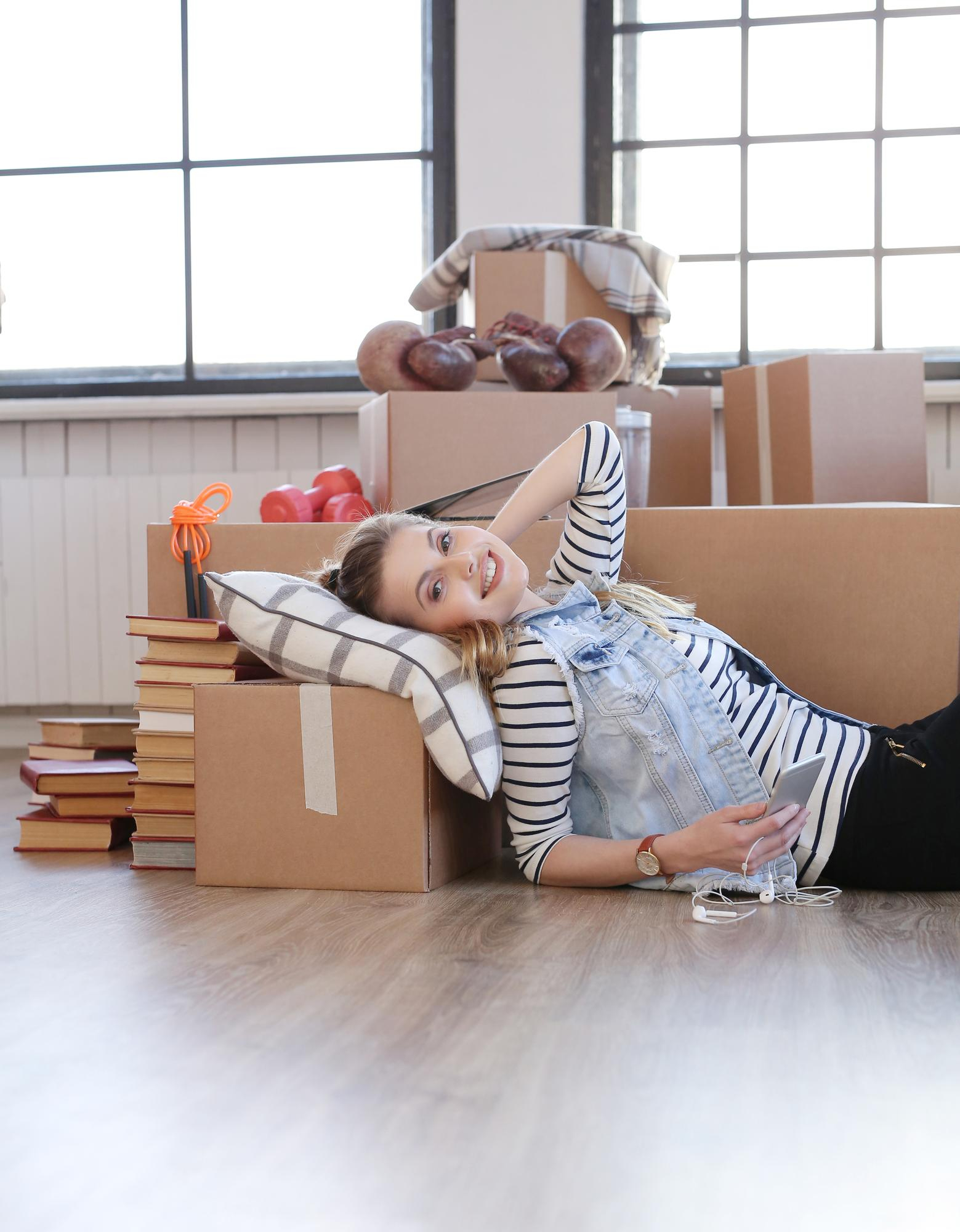 Woman relaxing on the floor among moving boxes